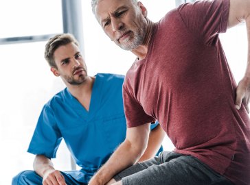 Foto eines Patienten, der einem Orthopäden zeigt, an welcher Stelle der Rücken schmerzt