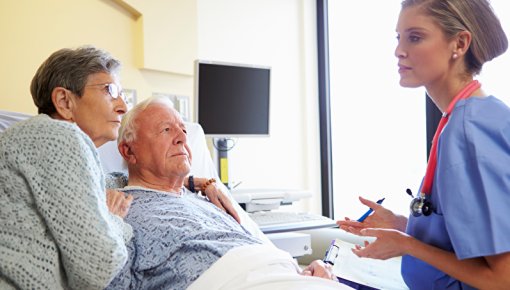 Foto von Patient und Partnerin im Gespräch mit einer Pflegekraft im Krankenhaus