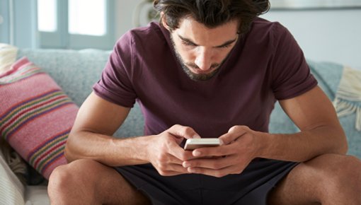 Junger Mann mit Smartphone auf Couch