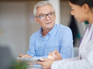 Foto eines älteren Mannes im Gespräch mit einer Ärztin