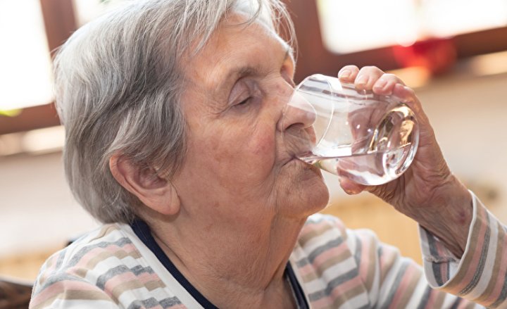 Foto einer Seniorin mit einem Glas Wasser